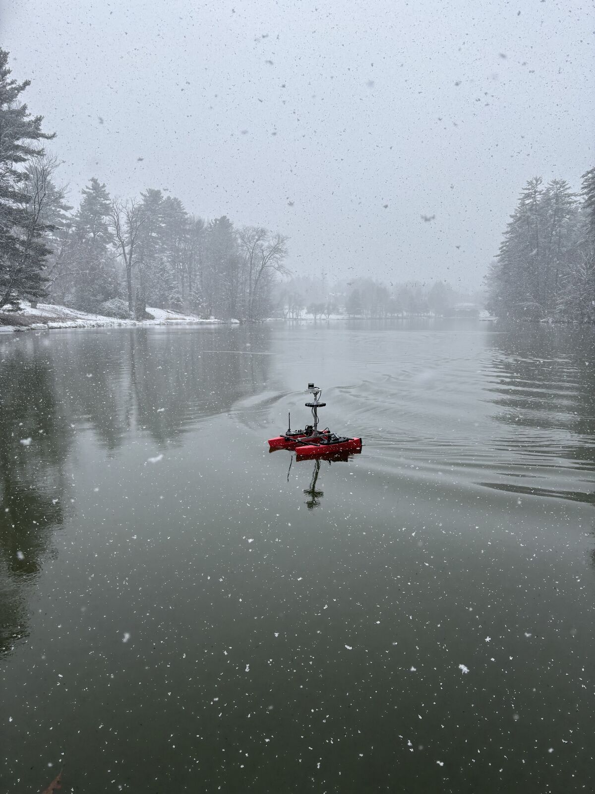 Red surface robot moving across a lake in falling snow